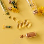 Flat lay of herbal supplements, dandelion flowers, and test tubes on a yellow background.