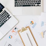 Overhead view of laptops, charts, and reports used for data analysis on a desk.